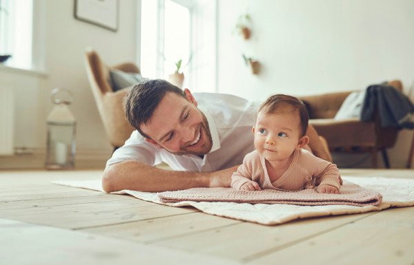 Smiling father lying with his infant daughter at home
